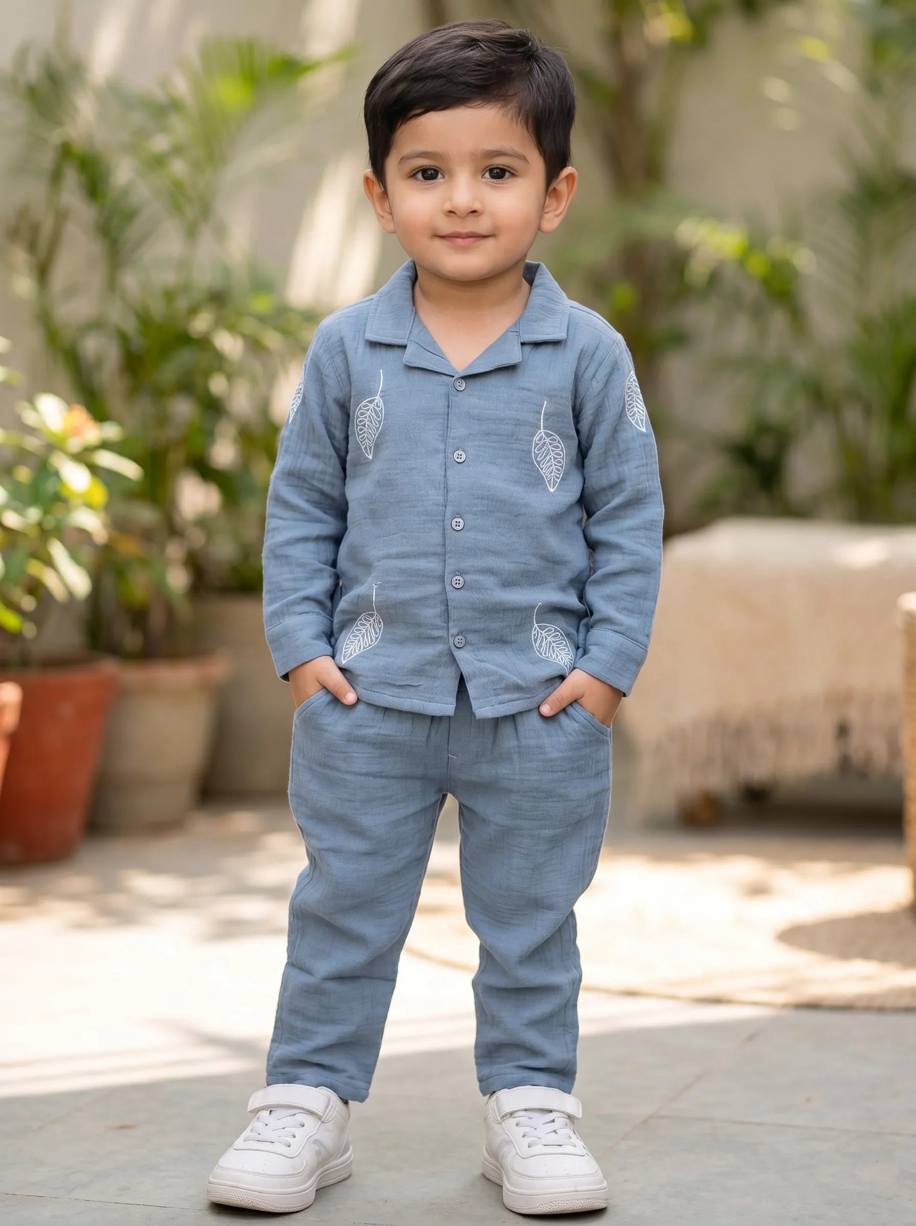Boy in a blue leaf print muslin shirt and trouser co-ord set by Boyz Fun