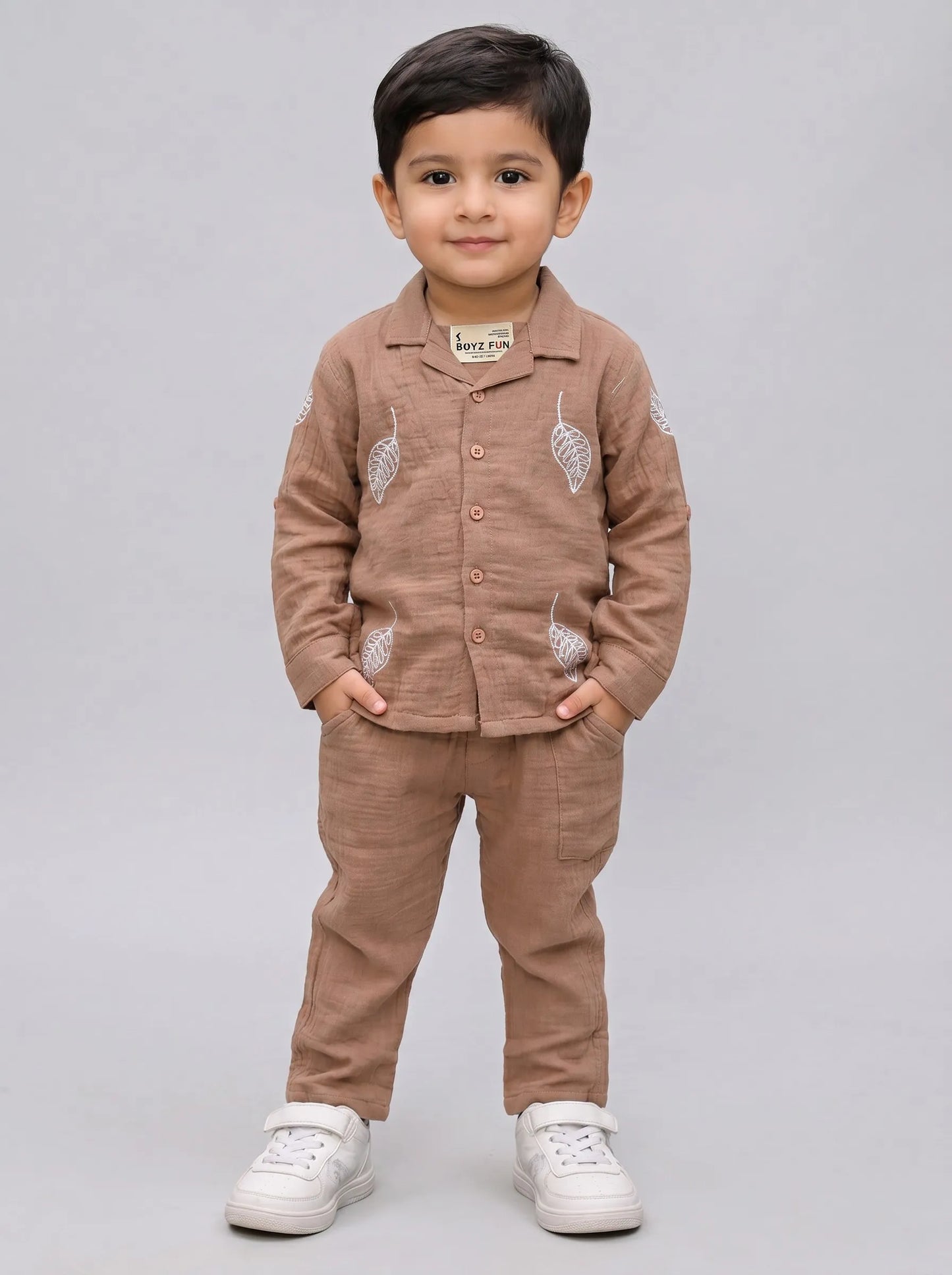 Boy in an orange leaf print muslin shirt and trouser co-ord set by Boyz Fun