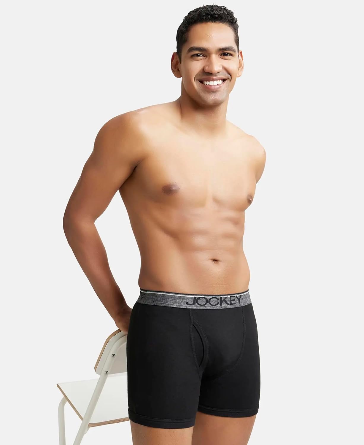 Model in Jockey black cotton boxer briefs standing beside a chair