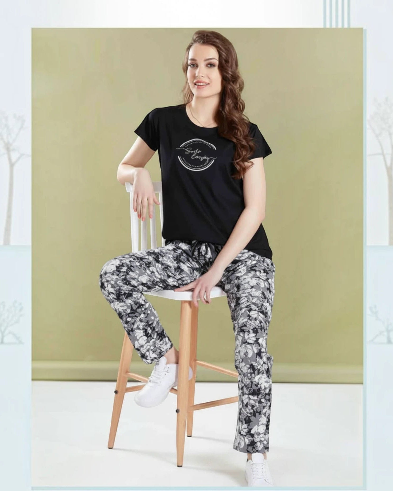 Woman seated on a stool in a black Smile Everyday tee and printed pyjama by In Touche