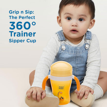 Baby gripping the orange Mee Mee 360 degree trainer sipper cup by its handles